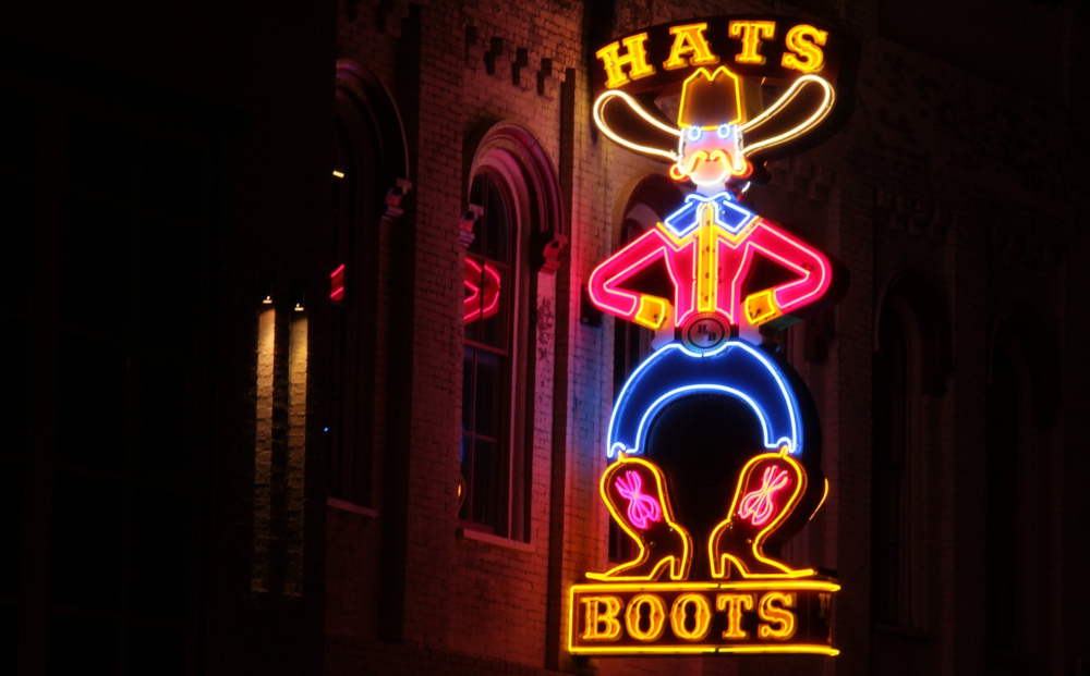 Neon sign of a cowboy advertising hats and boots is seen lit up at night on the side of a brick building in Nashville. Nashville may be famous for its music scene, but the state is clearly full of sports fans as well; TN's Handle Hit Record $386.1 Million