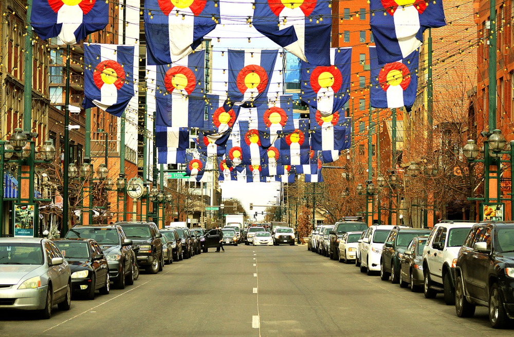 Larimer St in Denver. Cars line the street and hundreds of small Colorado flags hang above. 2021 was a breakout year for the Colorado sports betting industry. Data shows Coloradoans are big fans of pro basketball & pro football, placing more bets on those