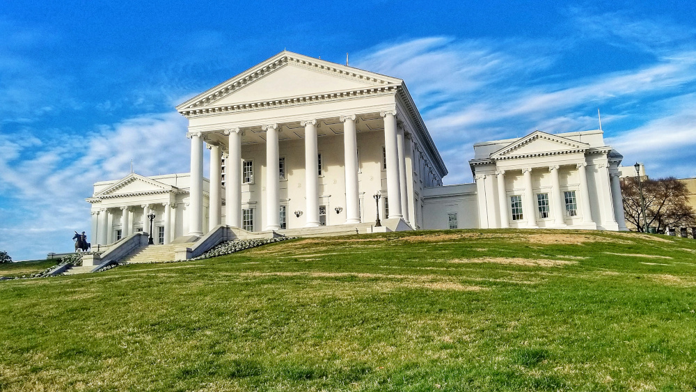 The Virginia State Capitol Building in Richmond, VA is seen atop a green hill, against a bright blue sky with fluffy clouds. State lawmakers are currently discussing various gaming bills that could mean big changes for the gambling industry.