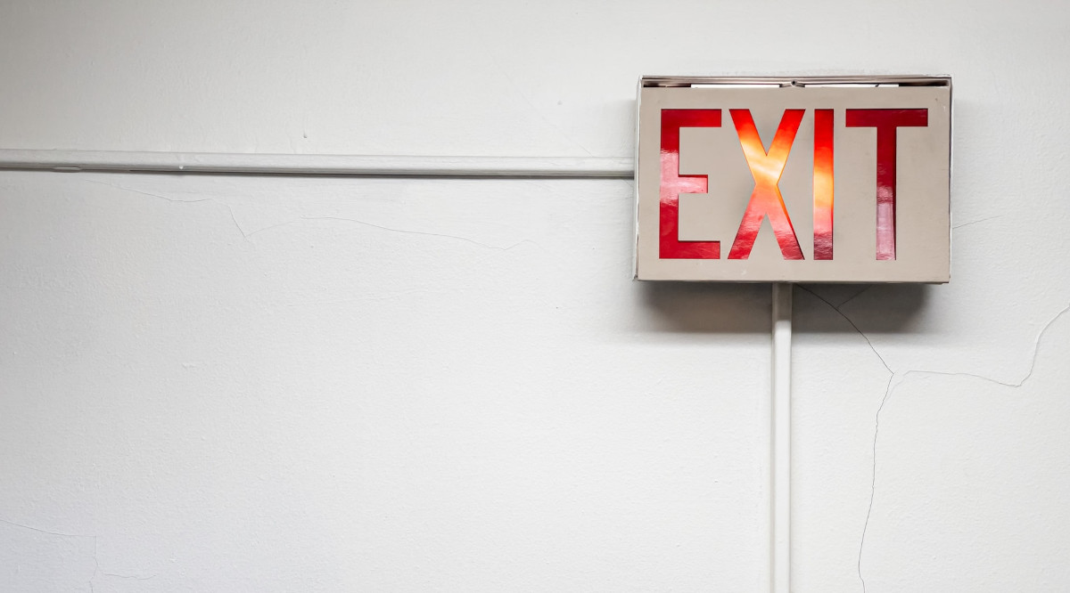 a red exit sign is seen on a white wall -- RSI announces withdrawal from Connecticut sports betting market in 2023
