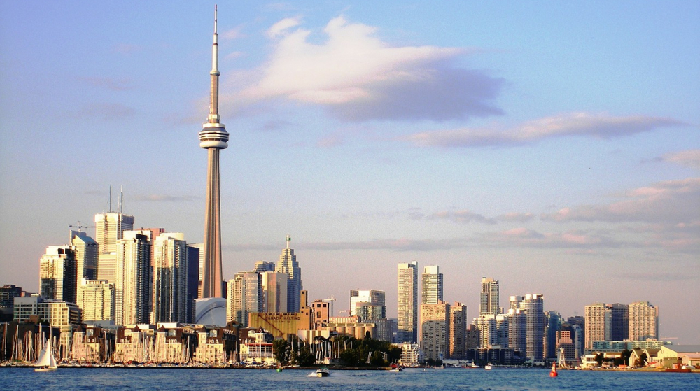 The skyline of Toronto in Ontario, Canada is seen across Lake Ontario at sunset with the CN Tower set against pink clouds. Canadian regulator says 30 iGaming operators have submitted applications. PokerStars, BetMGM, and WSOP reportedly all making plans