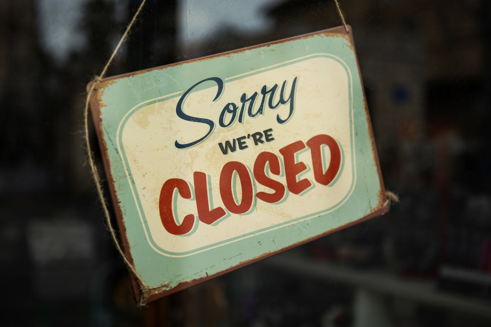 A shop window is seen with a retro-styled "Sorry we're closed" sign hanging in it. TwinSpires Preparing to Cease Ops in its Three Last States